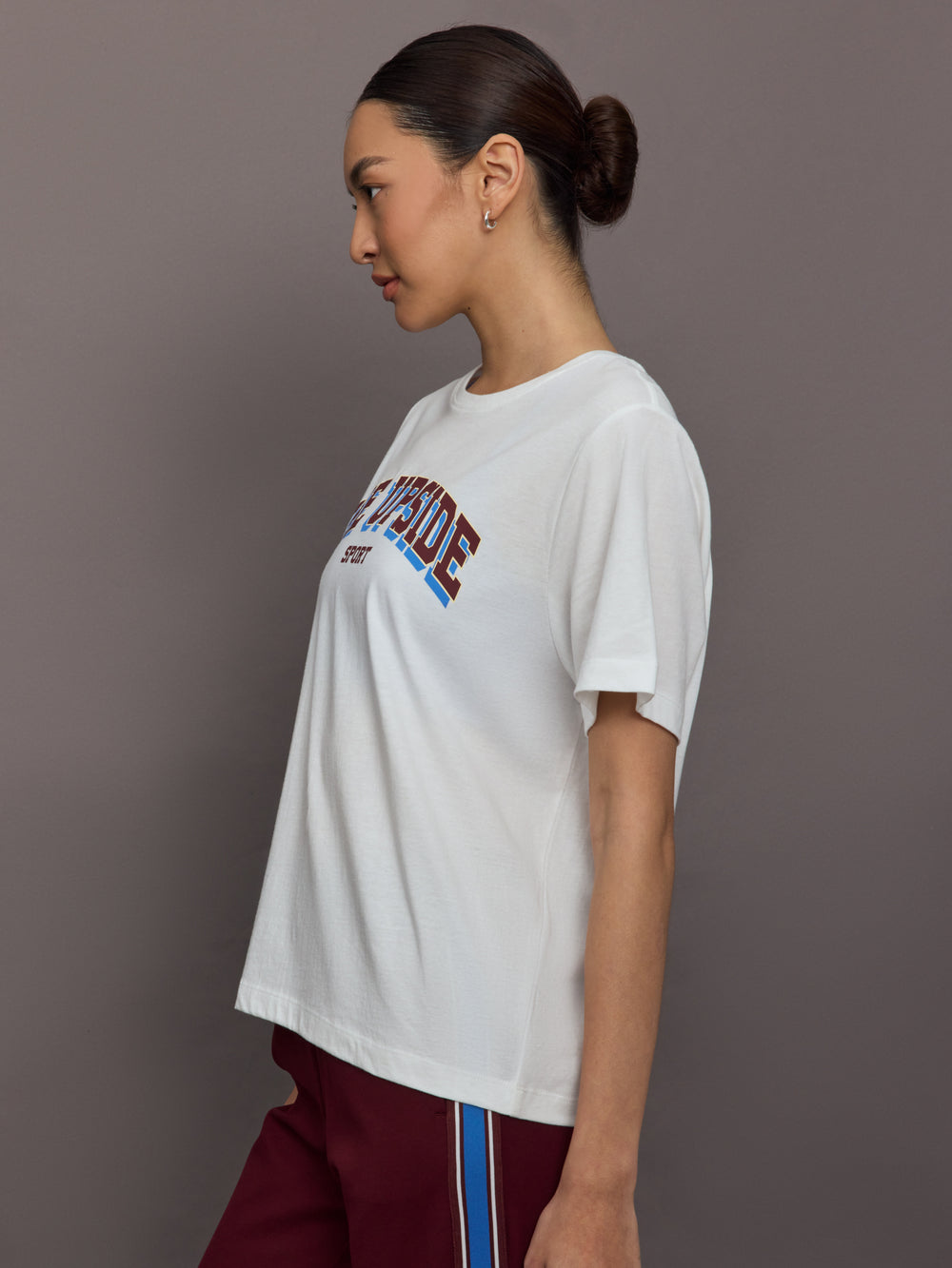 Woman wearing a white t-shirt with colorful text on a plain background