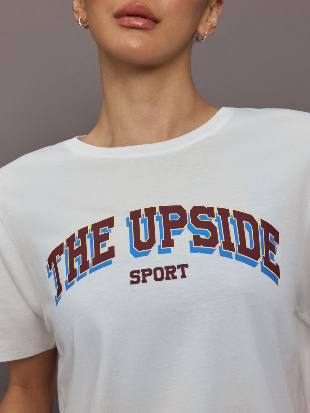 Person wearing a white t-shirt with 'THE UPSIDE SPORT' text