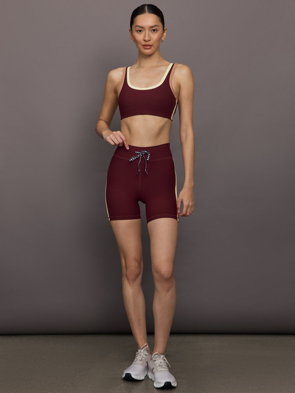 Model wearing a maroon sports bra with a beige trim.