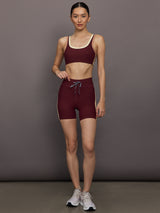 Model wearing a maroon sports bra with a beige trim.