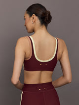 Model wearing a maroon sports bra with a beige trim.