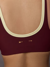 Model wearing a maroon sports bra with a beige trim.