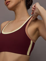 Model wearing a maroon sports bra with a beige trim.