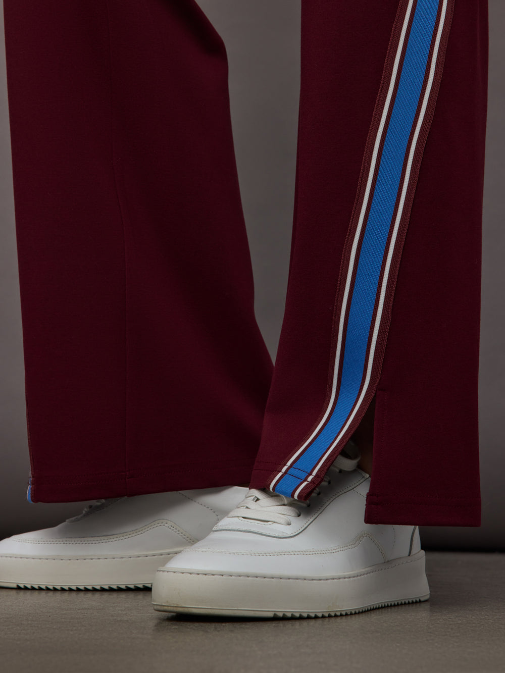 Model wears maroon pants with a blue stripe on each side.