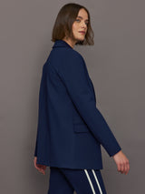 Model wears classic navy double-breasted blazer featuring structured shoulders and leopard detailing inside.