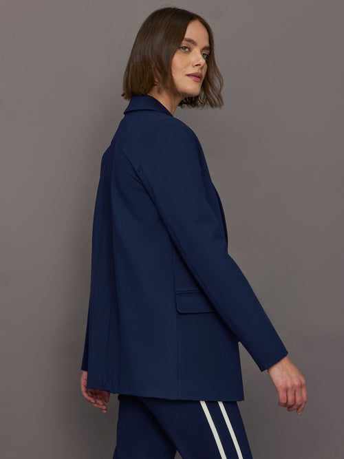 Model wears classic navy double-breasted blazer featuring structured shoulders and leopard detailing inside.