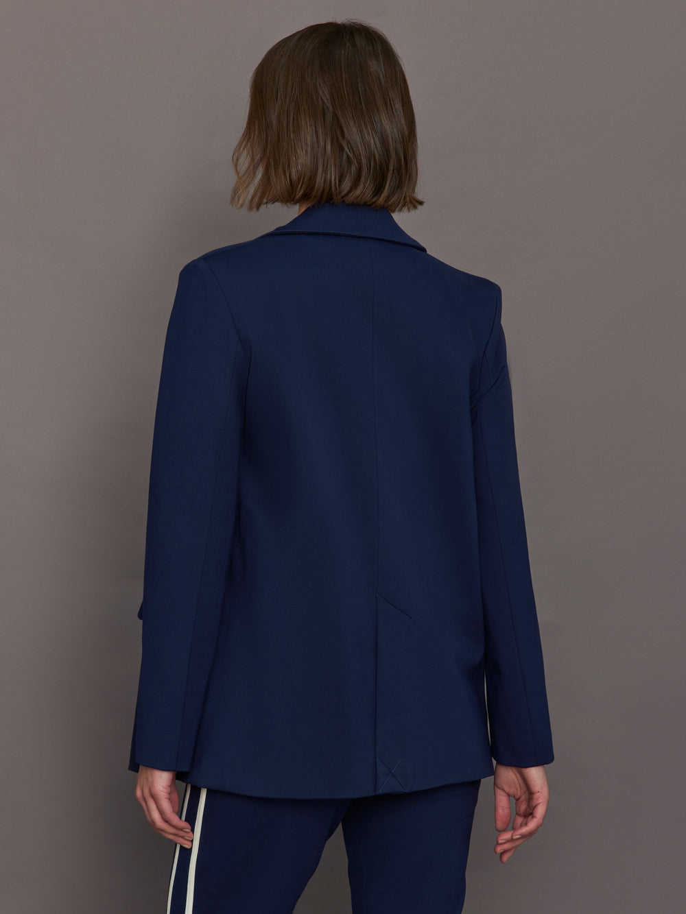 Model wears classic navy double-breasted blazer featuring structured shoulders and leopard detailing inside.