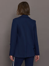 Model wears classic navy double-breasted blazer featuring structured shoulders and leopard detailing inside.