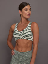 Woman wearing a zebra print sports bra and gray leggings against a gray background