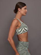 Woman wearing a zebra print sports bra and leggings against a gray background