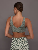 Person wearing a green sports bra and zebra print leggings against a gray background