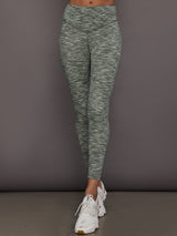 Person wearing green marbled leggings and white sneakers on a gray background