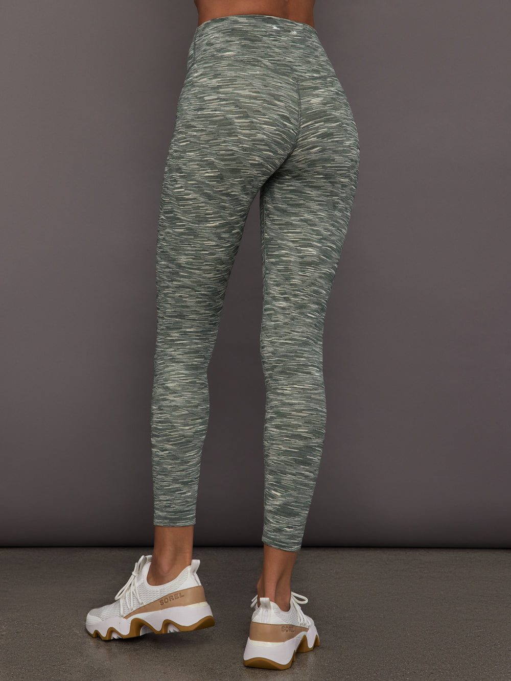 Person wearing green marbled leggings on a gray background