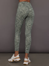 Person wearing green marbled leggings on a gray background