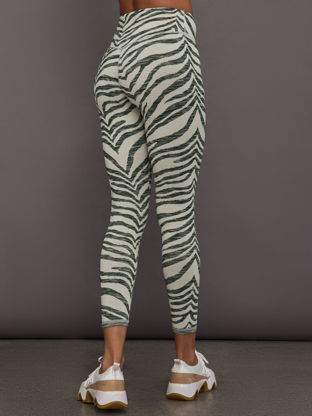 Person wearing zebra print leggings against a gray background