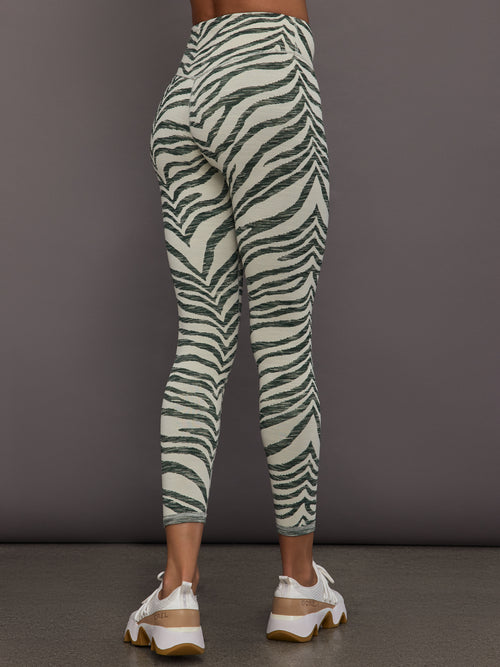 Person wearing zebra print leggings against a gray background