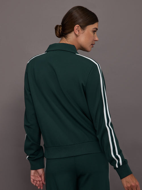 Person wearing a green tracksuit with white stripes on a gray background