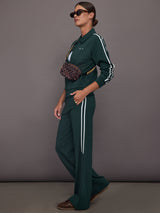 Woman wearing a green tracksuit with white stripes on a gray background