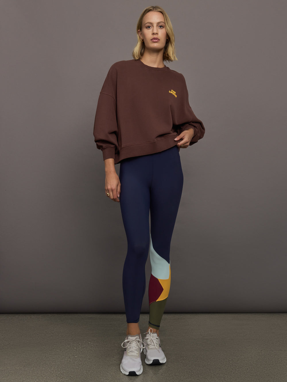 Model wearing a brown sweatshirt with 'The Upside' logo
