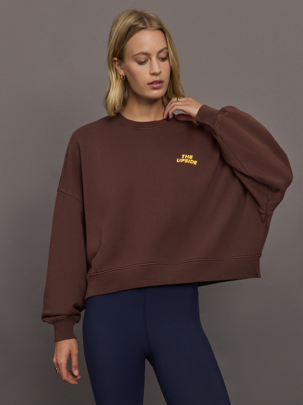 Model wearing a brown sweatshirt with 'The Upside' logo