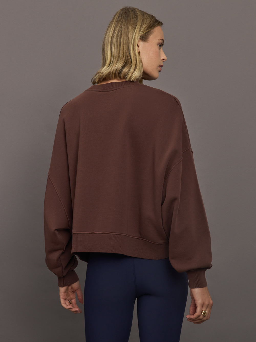 Model wearing a brown sweatshirt with 'The Upside' logo