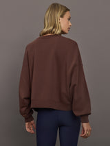 Model wearing a brown sweatshirt with 'The Upside' logo