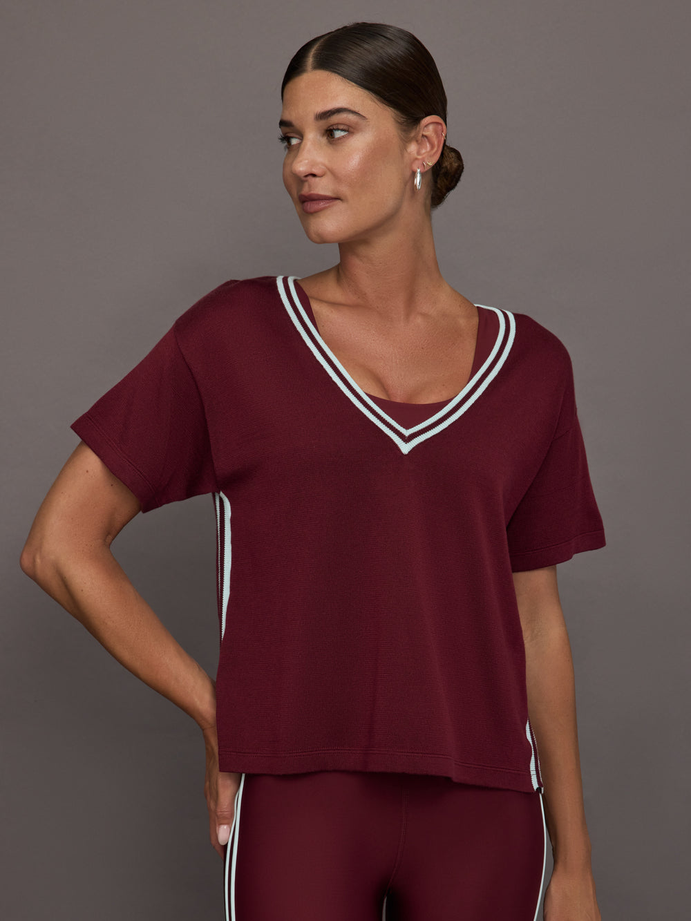 Model wears an oversized burgundy V neck t-shirt with white contrast piping.