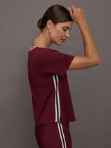 Model wears an oversized burgundy V neck t-shirt with white contrast piping.