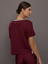 Model wears an oversized burgundy V neck t-shirt with white contrast piping.