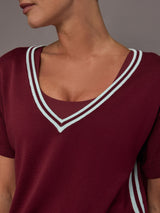 Model wears an oversized burgundy V neck t-shirt with white contrast piping.