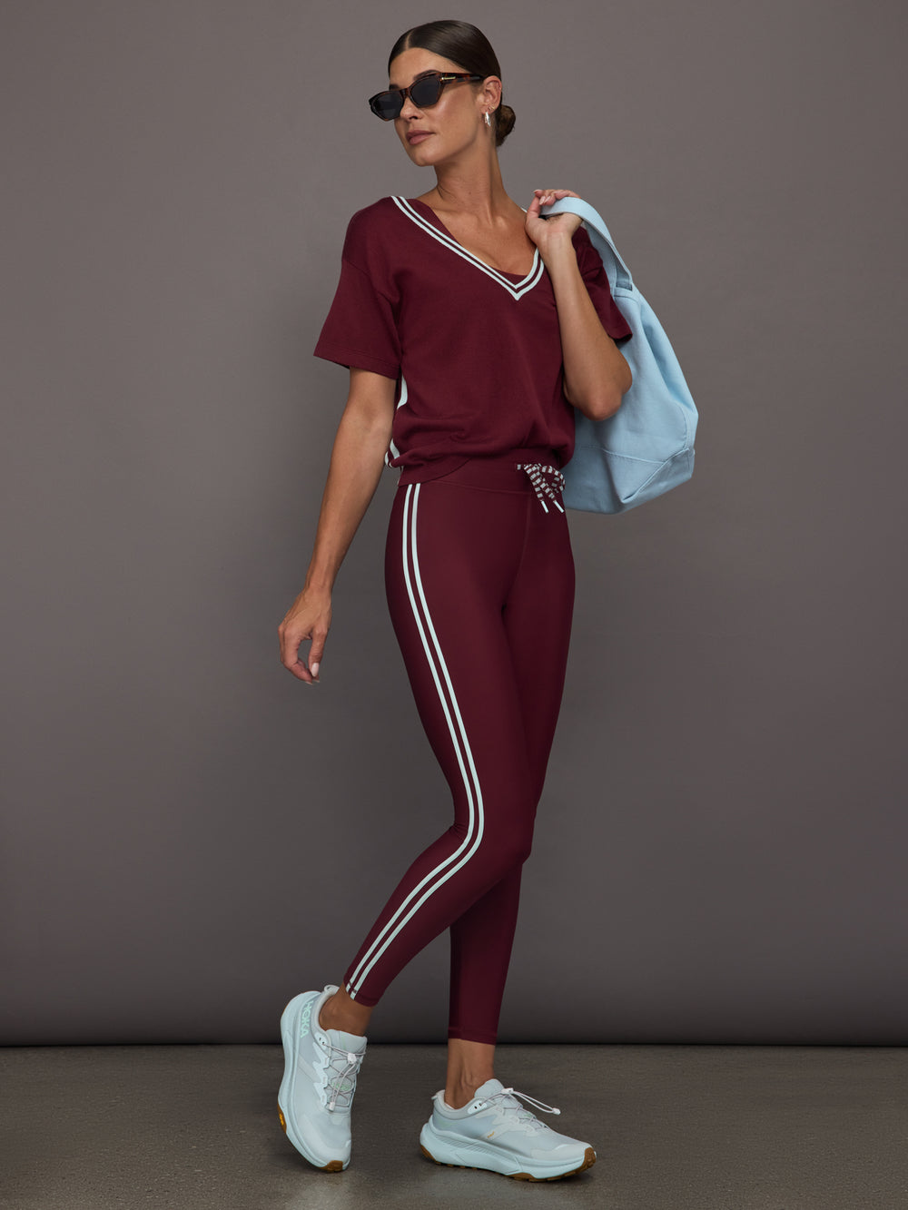 Model wears an oversized burgundy V neck t-shirt with white contrast piping.