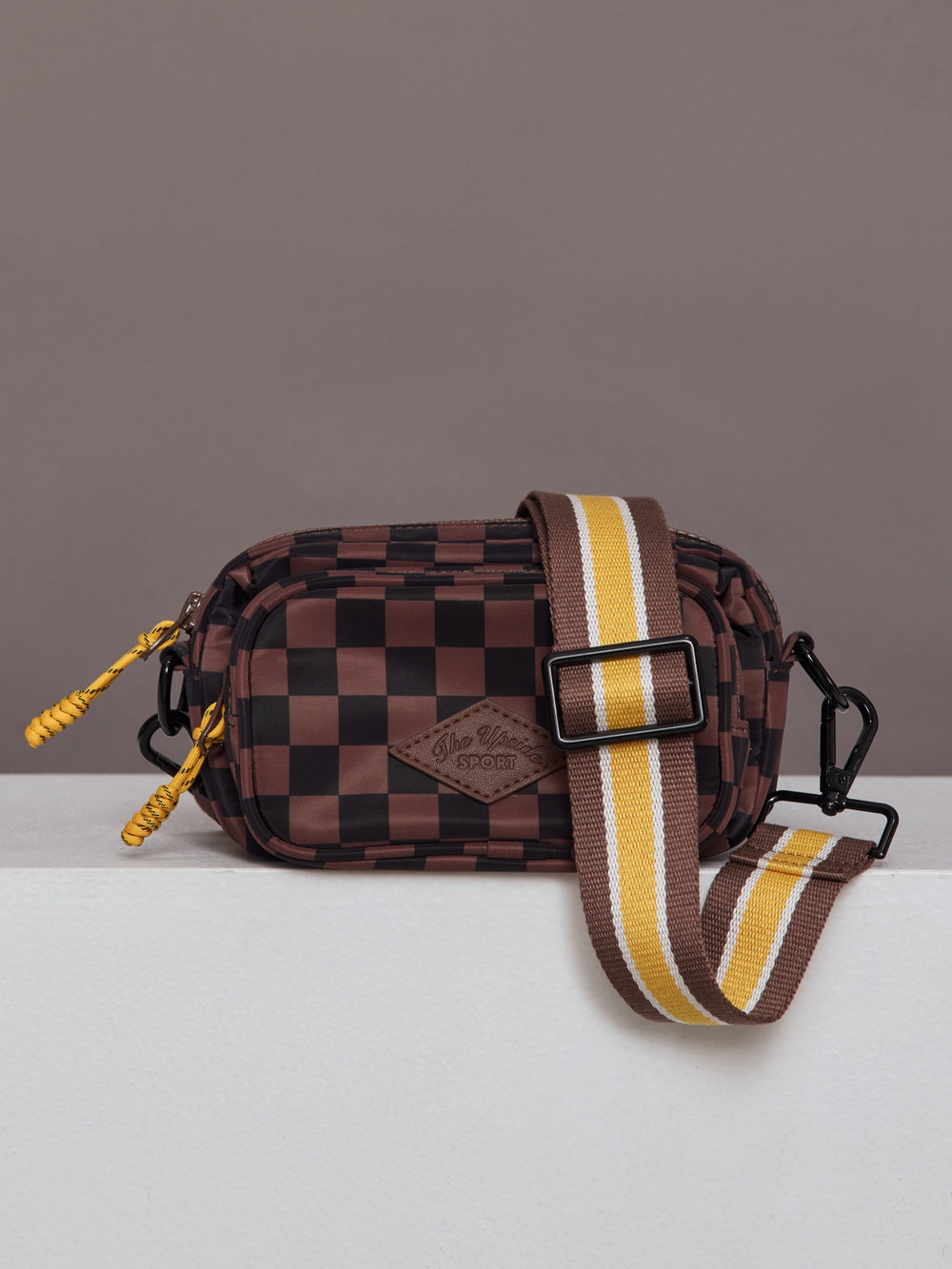Model wearing brown and black checkered crossbody bag.