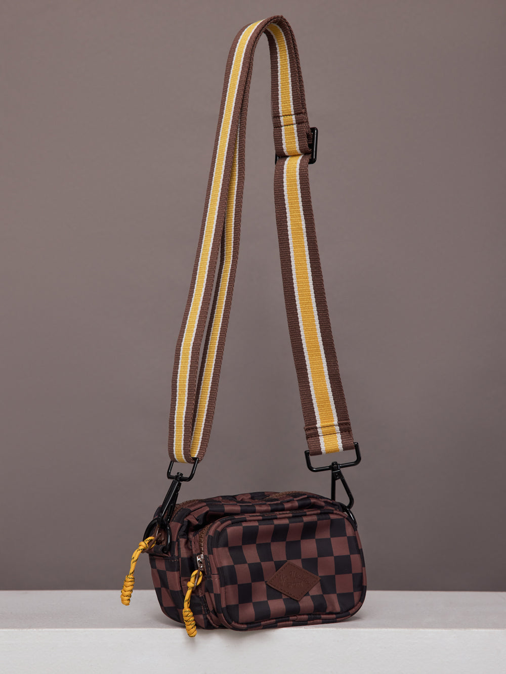 Model wearing brown and black checkered crossbody bag.