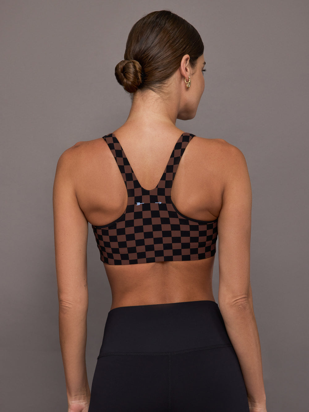 Woman wearing a checkered black and brown sports bra.