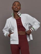 Model wears white track jacket with a high collar, front zipper, and ribbed cuffs and hem.




