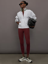 Model wears white track jacket with a high collar, front zipper, and ribbed cuffs and hem.
