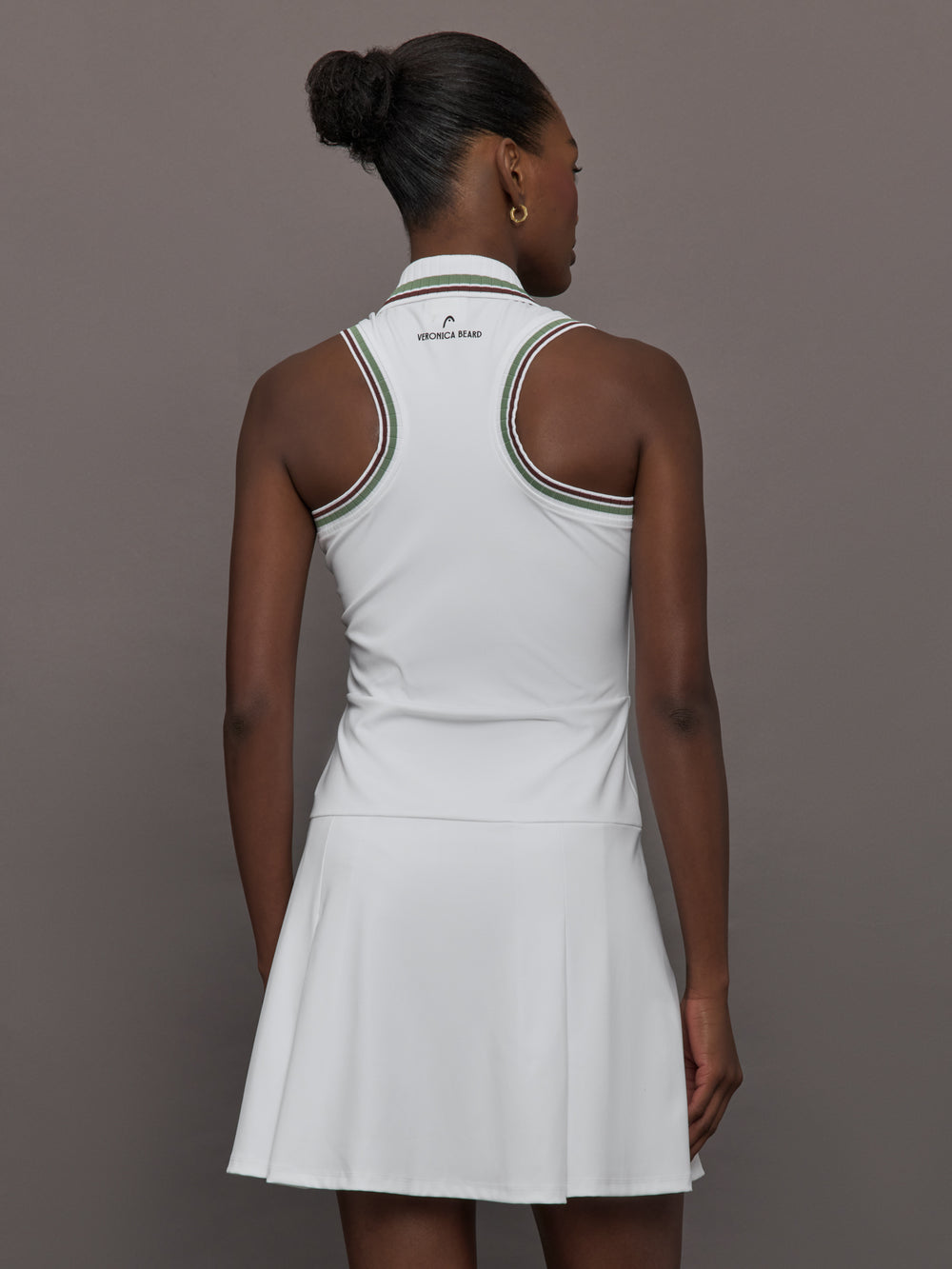 Model wears white sleeveless dress with a fitted bodice and flared skirt, and a collared neck.
