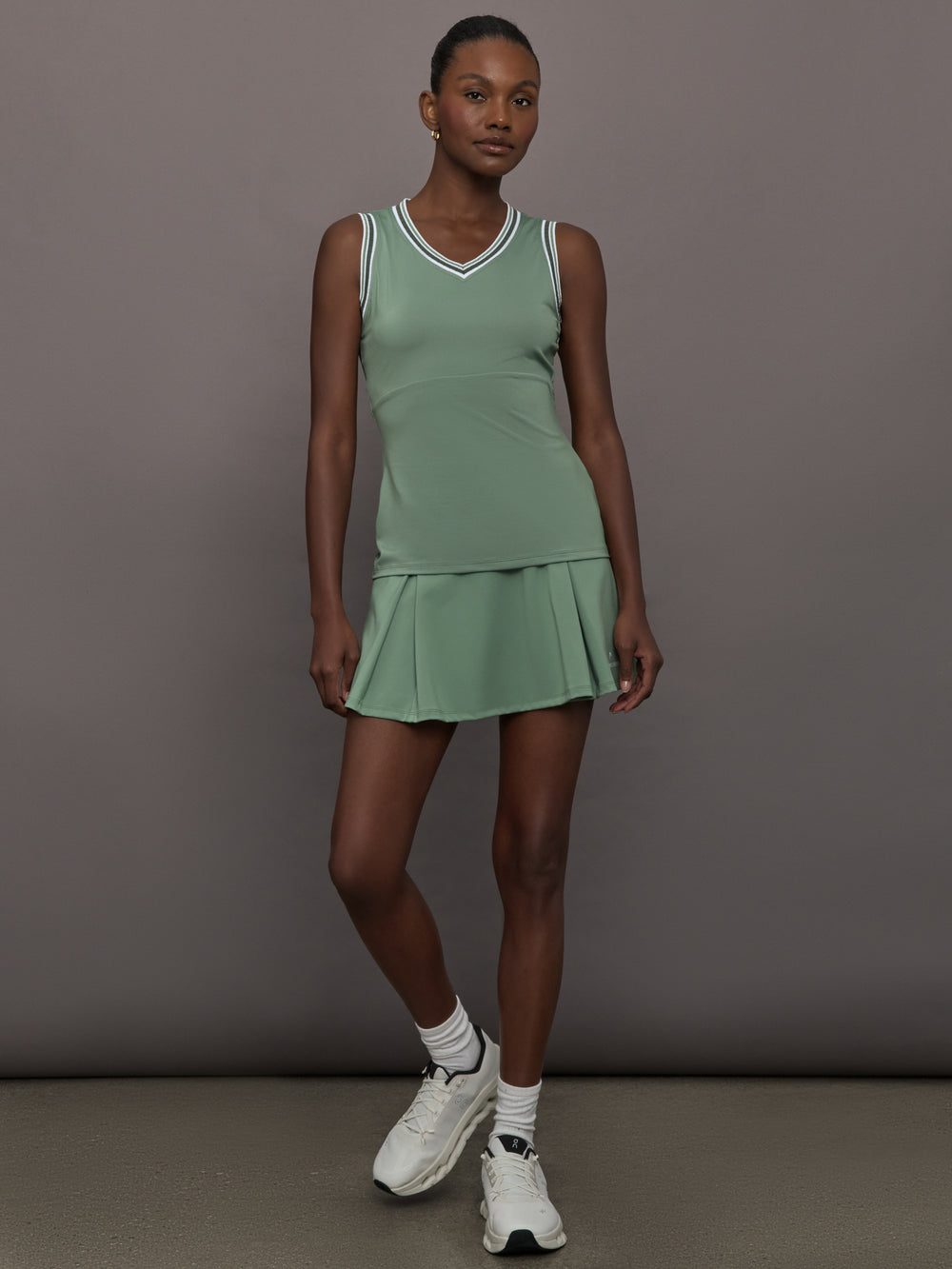 Model wears sage green tank top with a v-neckline and a fitted design.