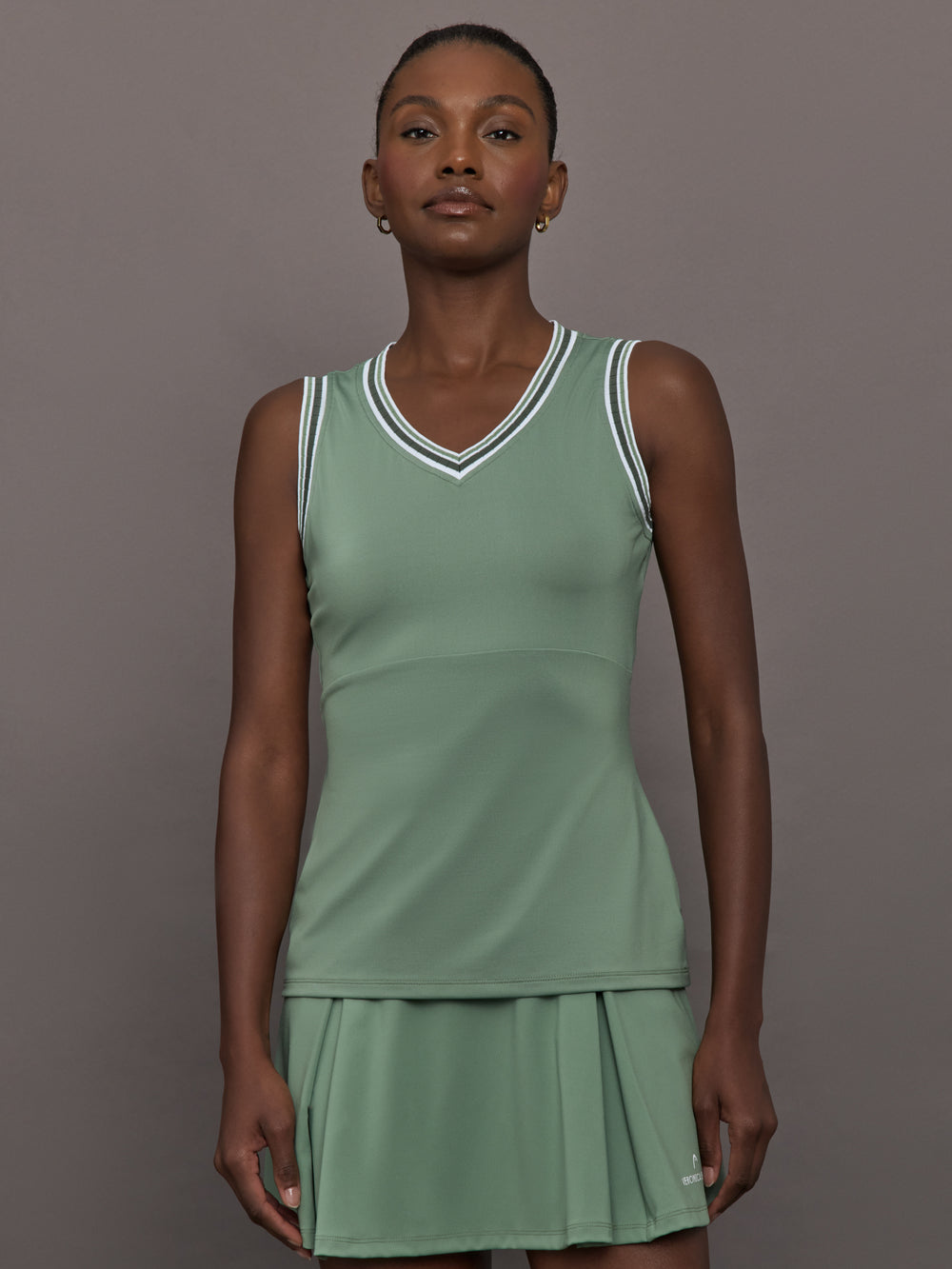 Model wears sage green tank top with a v-neckline and a fitted design.