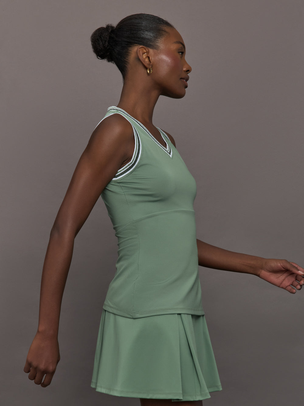 Model wears sage green tank top with a v-neckline and a fitted design.