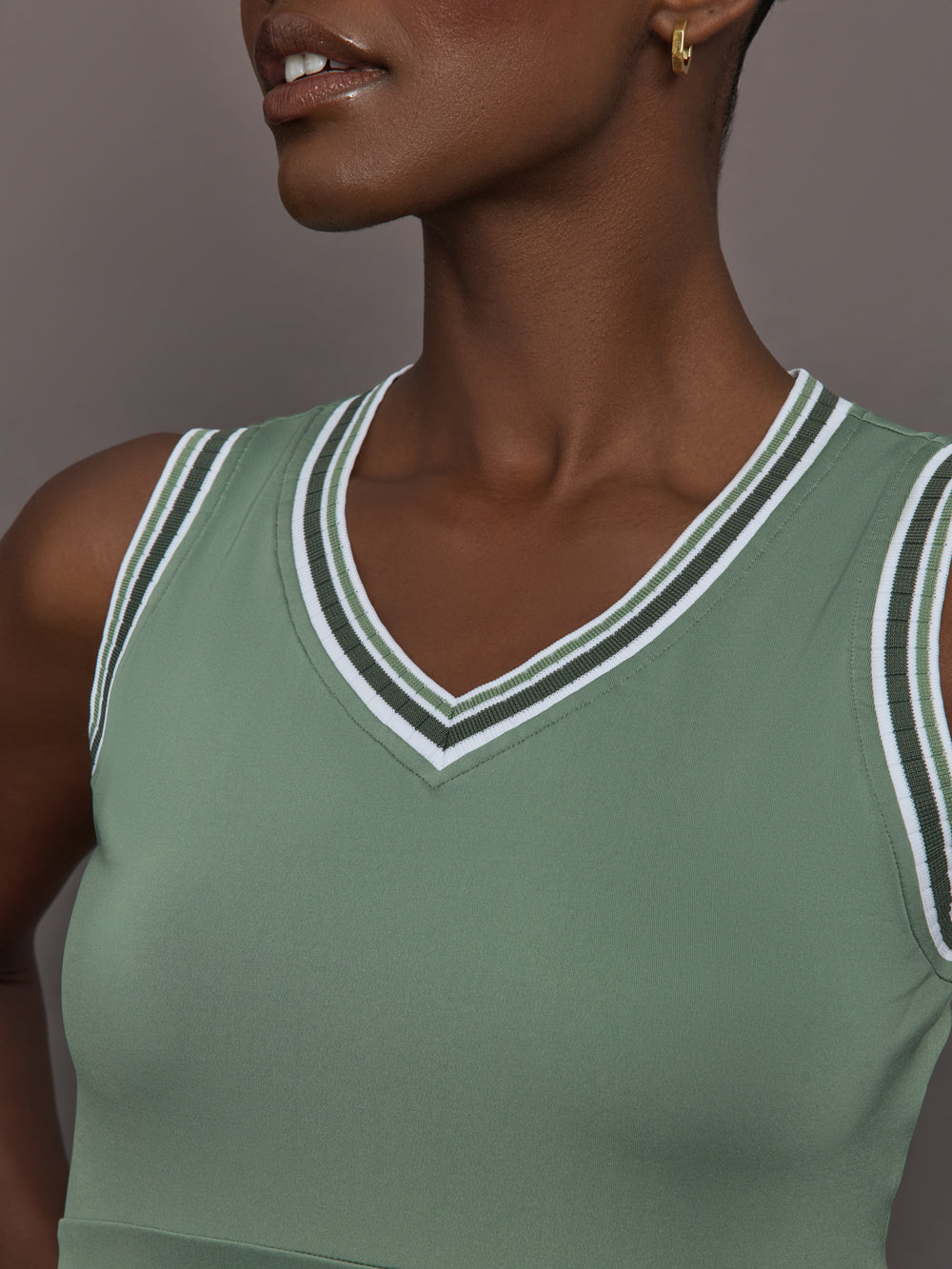 Model wears sage green tank top with a v-neckline and a fitted design.