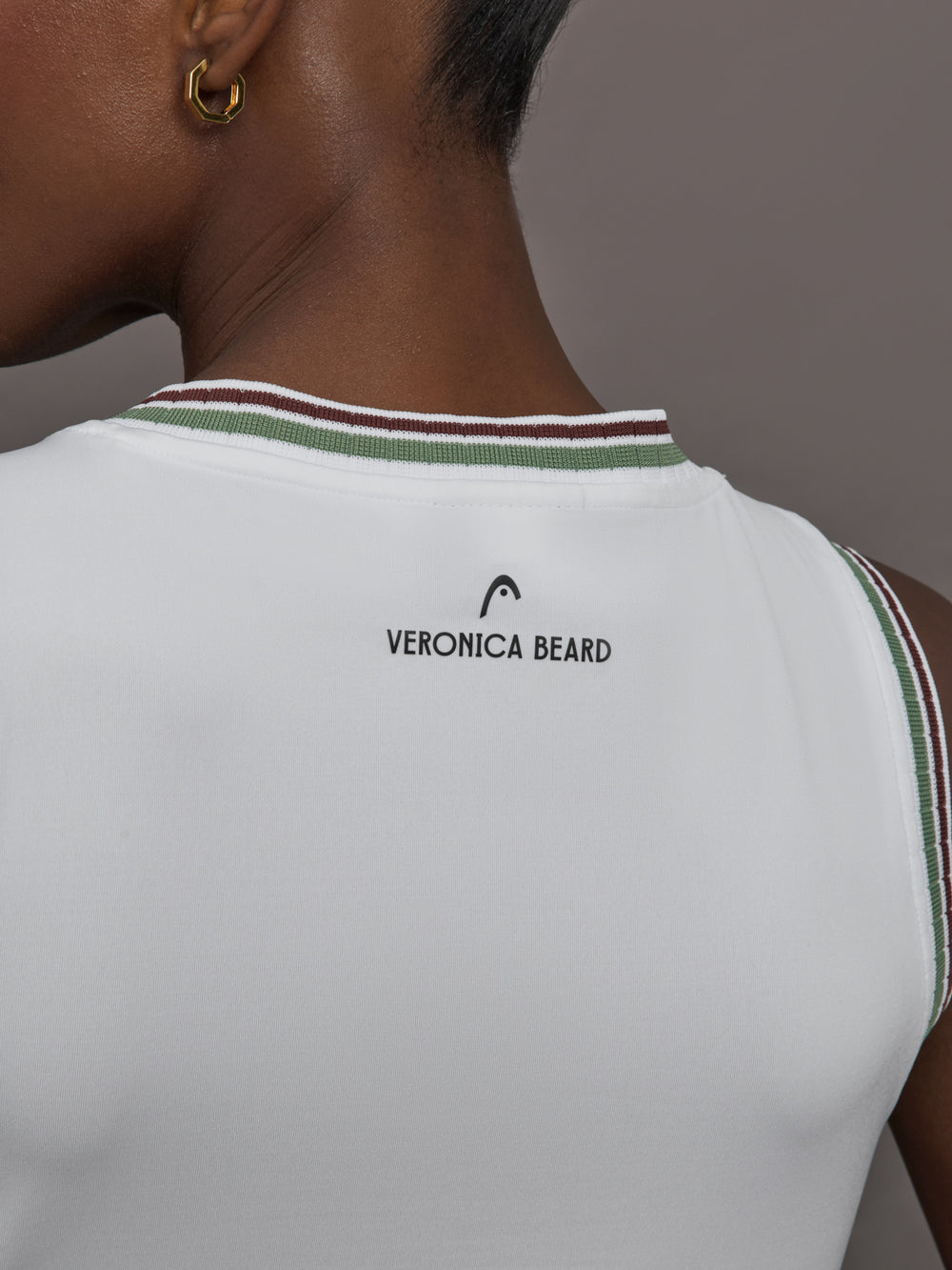 Model wears white tank top with a v-neckline and a fitted design.