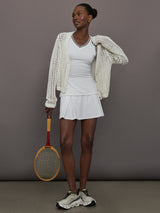Model wears white tank top with a v-neckline and a fitted design.
