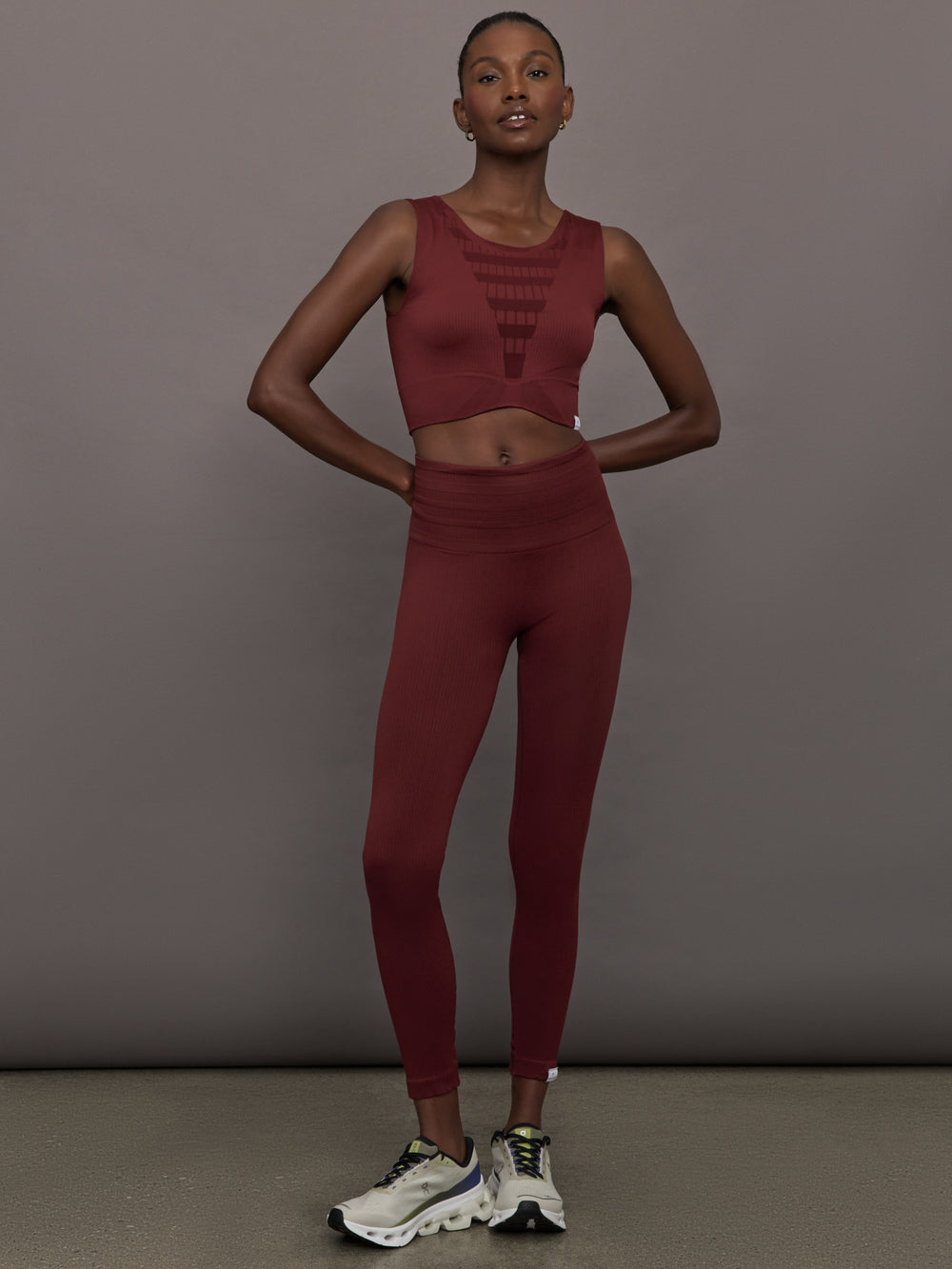 Model wears sports bra in Terracotta with a high neckline and a subtle patterned detailing in the center front.
