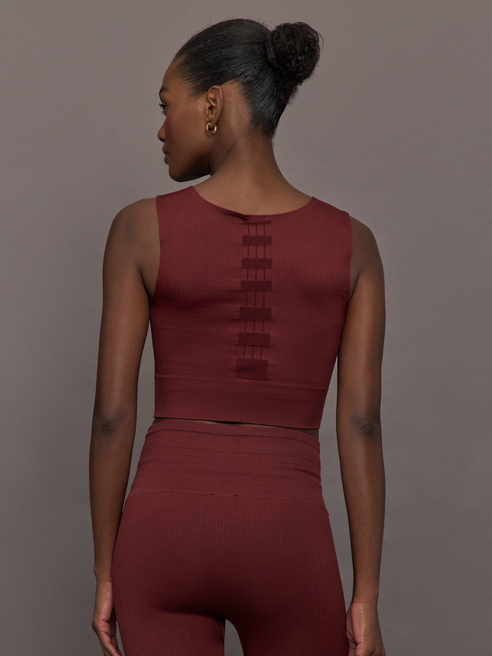 Model wears sports bra in Terracotta with a high neckline and a subtle patterned detailing in the center front.
