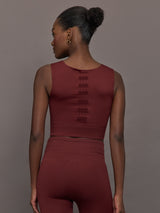 Model wears sports bra in Terracotta with a high neckline and a subtle patterned detailing in the center front.

