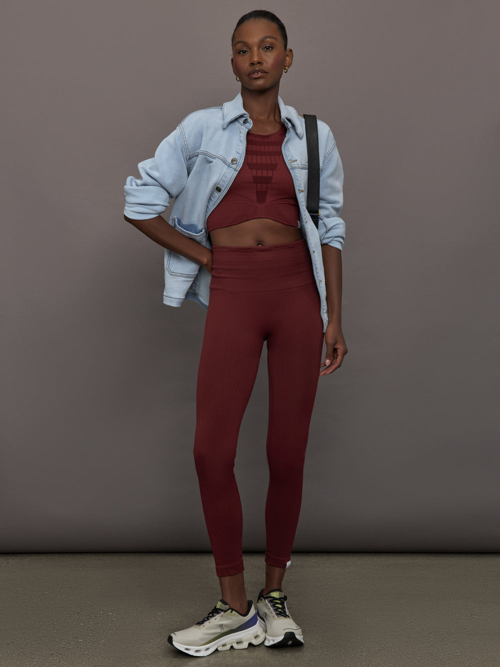 Model wears sports bra in Terracotta with a high neckline and a subtle patterned detailing in the center front.

