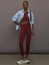 Model wears sports bra in Terracotta with a high neckline and a subtle patterned detailing in the center front.
