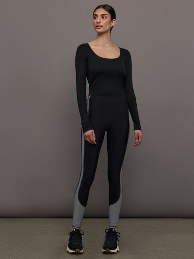 Model wears a long sleeved scoop neck black crop top. 