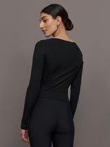 Model wears a long sleeved scoop neck black crop top. 